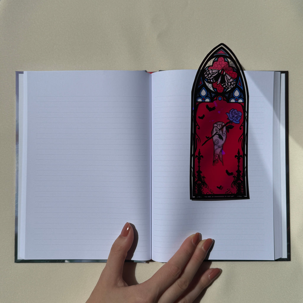 Carnet ouvert sur ses pages lignées, avec un marque-page vitrail rouge posé dessus