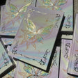 Plusieurs carnets de lecture empilés au soleil, couvertures irisées à papillon doré
